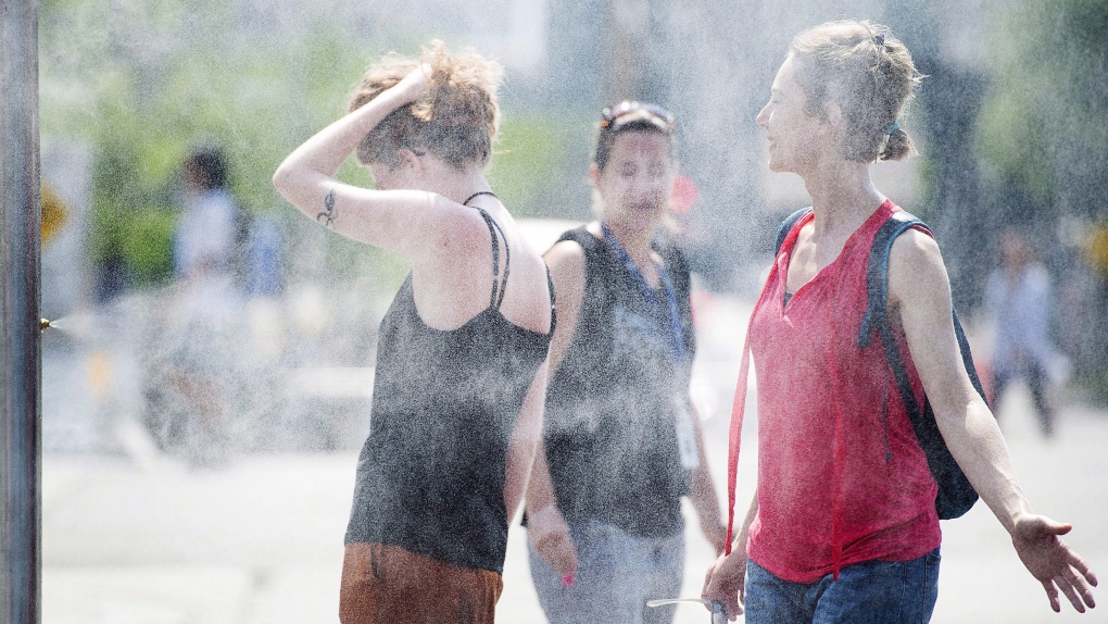 People use misters to cool down during a heatwave in Montreal, on July 2, 2018. (THE CANADIAN PRESS/Graham Hughes)