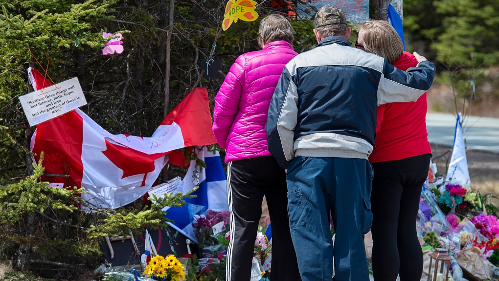 A family pays their respects to victims of the mass killings at a checkpoint on Portapique Road in Portapique, N.S. (THE CANADIAN PRESS/Andrew Vaughan)