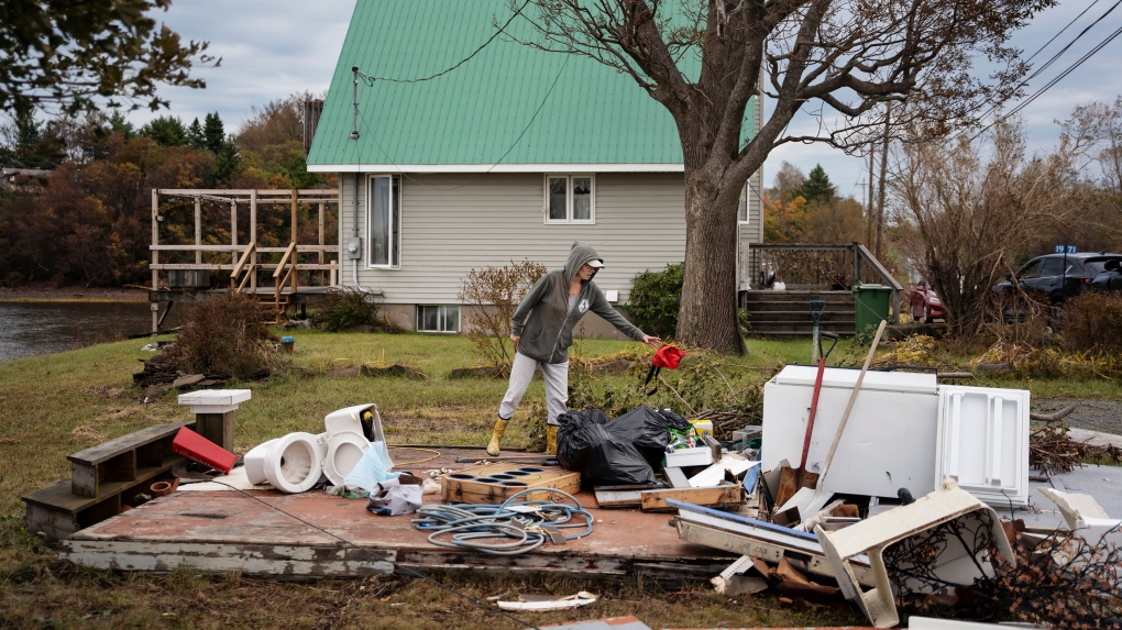 Michelle MacInnis clears debris in her yard near Merigomish in Pictou County, N.S., on Wednesday, September 28, 2022 following significant damage brought by post tropical storm Fiona. THE CANADIAN PRESS/Darren Calabrese 