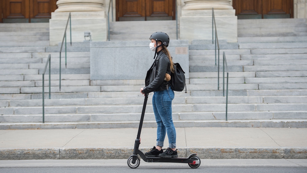 A woman wears a face mask as she rides a scooter by the Museum of Fine Arts in Montreal, Sunday, May 31, 2020, THE CANADIAN PRESS/Graham Hughes 