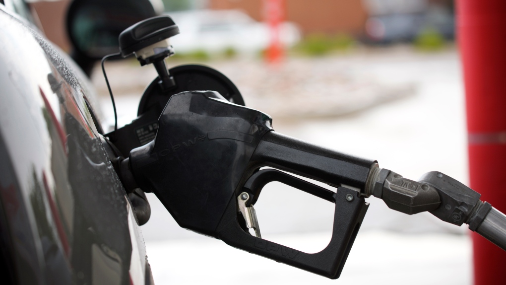 The handle from a gasoline pump hangs from the filler neck of a motorist's vehicle at a Shell station Saturday, July 31, 2021, in Englewood, Colo. (AP Photo/David Zalubowski) 