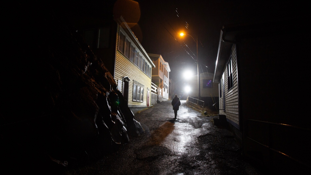 Residents of a historic St. Johns, N.L., fishing neighbourhood have been left in the dark after a pair of floodlights that had been shining into homes since last May suddenly shut off on Thursday night. A woman walks in her neighbourhood in the Battery historical area of St. John's NL on Monday, January 16, 2023. THE CANADIAN PRESS/Paul Daly