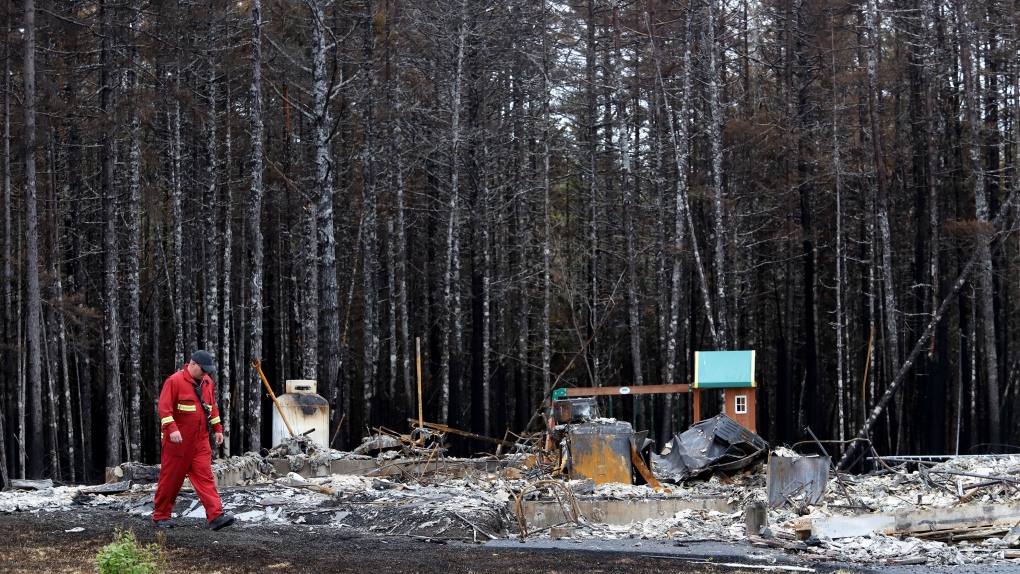 A firefighter walks past a home destroyed by a wildfire in Hammonds Plains, N.S., during a media tour, Tuesday, June 6, 2023. THE CANADIAN PRESS/POOL, Tim Krochak