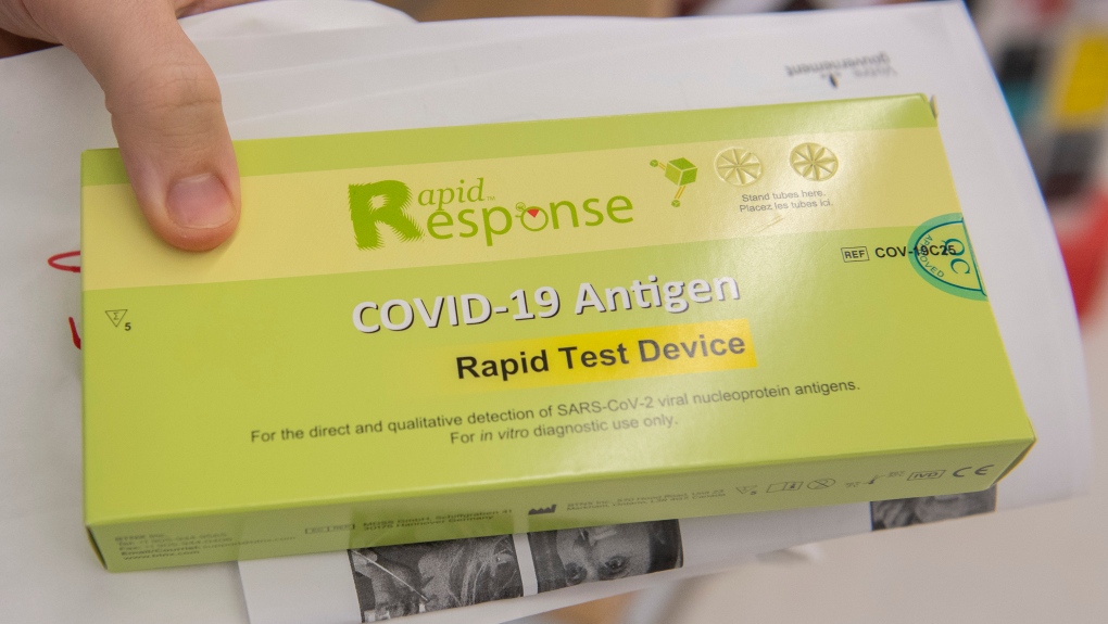 A man displays his COVID-19 rapid test kit after receiving it at a pharmacy in Montreal, Monday, December 20, 2021, as the COVID-19 pandemic continues in Canada and around the world. THE CANADIAN PRESS/Graham Hughes 